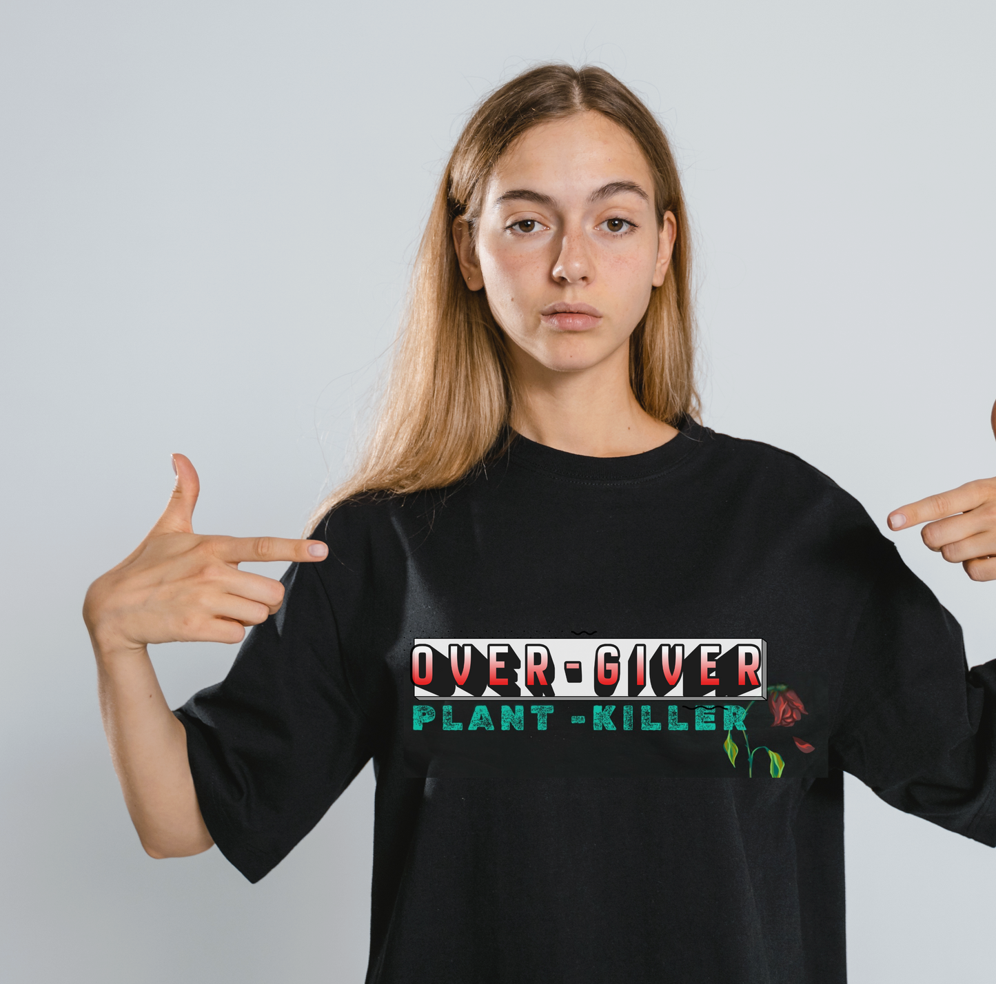Person wearing a black t-shirt with 'OVER-GIVER PLANT-KILLER' text and pointing at it.